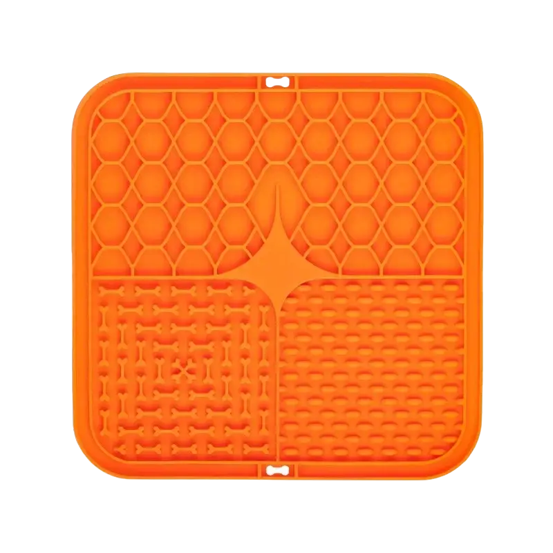 Bright orange slow feeder pet lick silicone mat with honeycomb pattern and bone cutouts for controlled mealtime