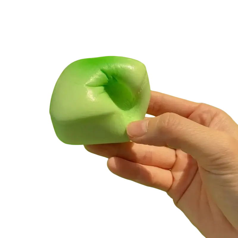 A hand holds a light green slow rising squishy mini toast toy with a glossy surface and subtle top indentation