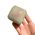 Slow rising squishy mini toast fidget toy in pale green speckled square soap bar with subtle pinkish hue on surface