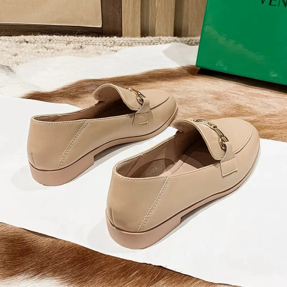 Beige leather women’s loafers with gold-tone chain detail and silver horsebit buckle on the vamp