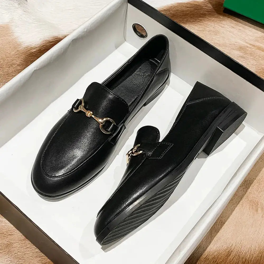 Women’s black leather loafers with gold-tone horsebit buckle and low block heels showing front view