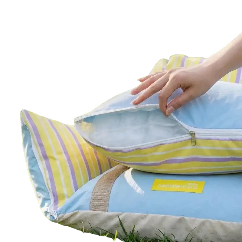 Small dog car seat and travel bed with light blue and yellow striped pillow featuring zipper closure on grass