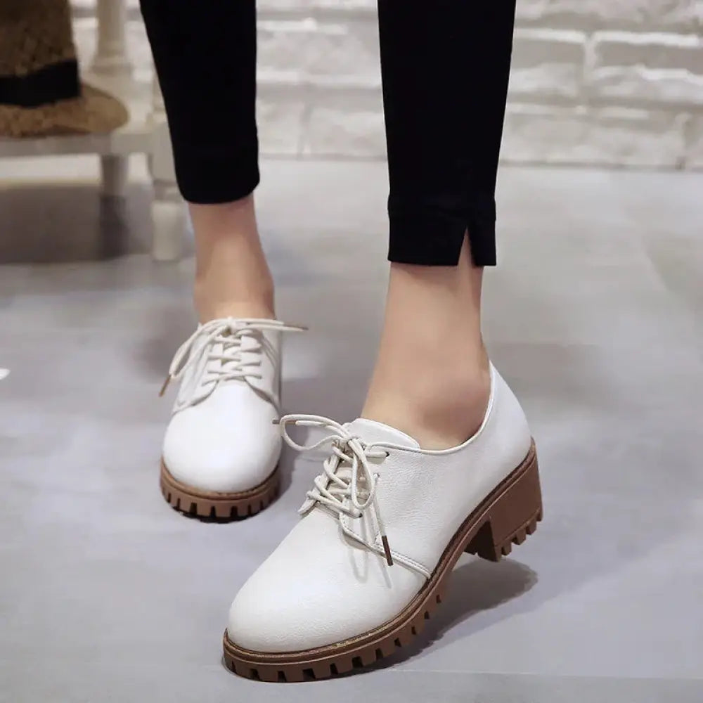 White leather lace-up oxford shoes for women with a chunky brown rubber sole perfect for formal or casual wear