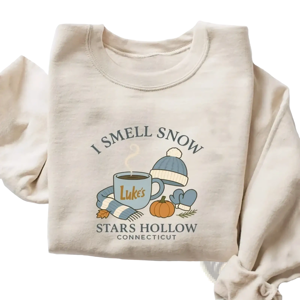 Beige long-sleeved i smell snow christmas sweatshirt with cozy autumn-themed graphic of mug hat scarf and pumpkin