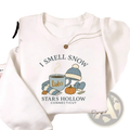 White crewneck sweatshirt featuring cozy autumn graphic with i smell snow text and stars hollow connecticut details