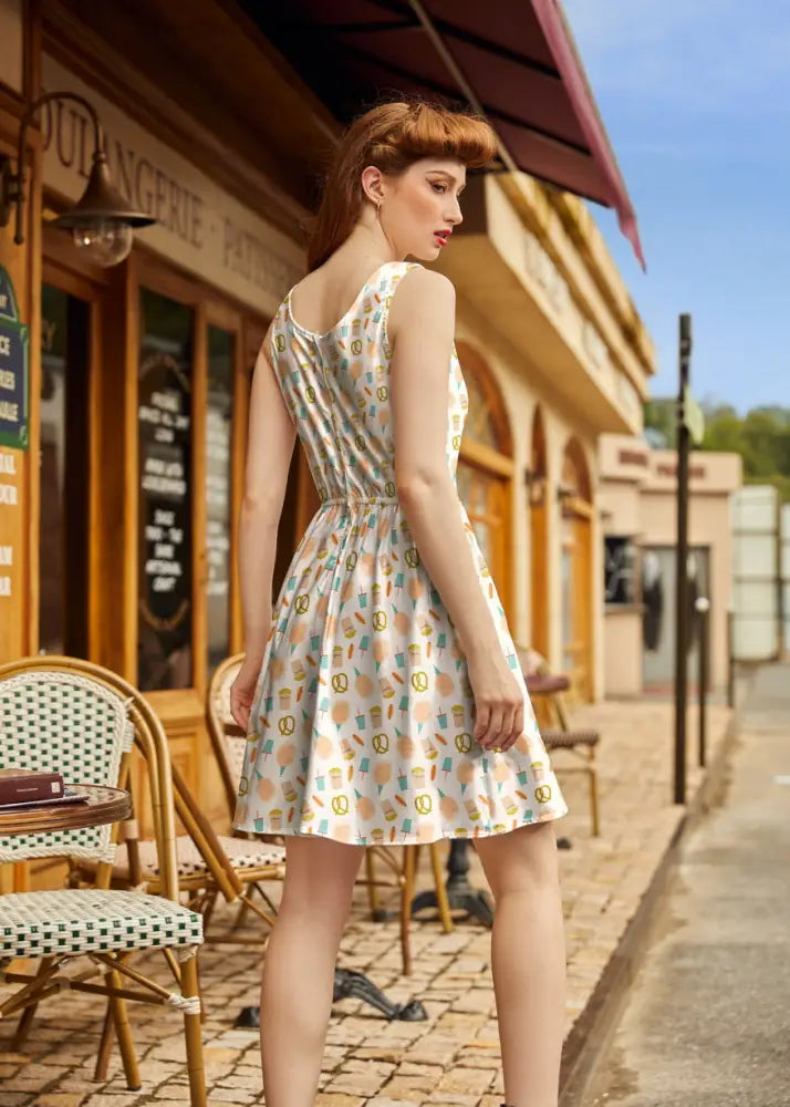 A sleeveless knee-length vintage carnival snacks fit and flare cotton dress in cream with pastel ice cream cones and pretzels pattern