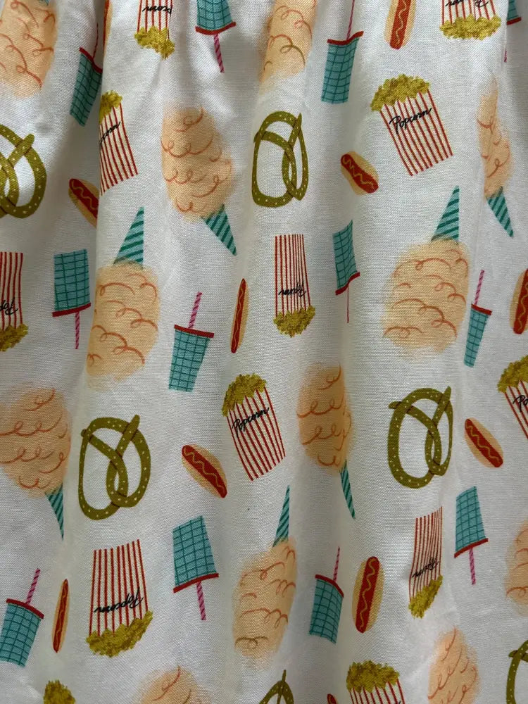 White fit and flare cotton dress with playful vintage carnival snack illustrations including pretzels and popcorn