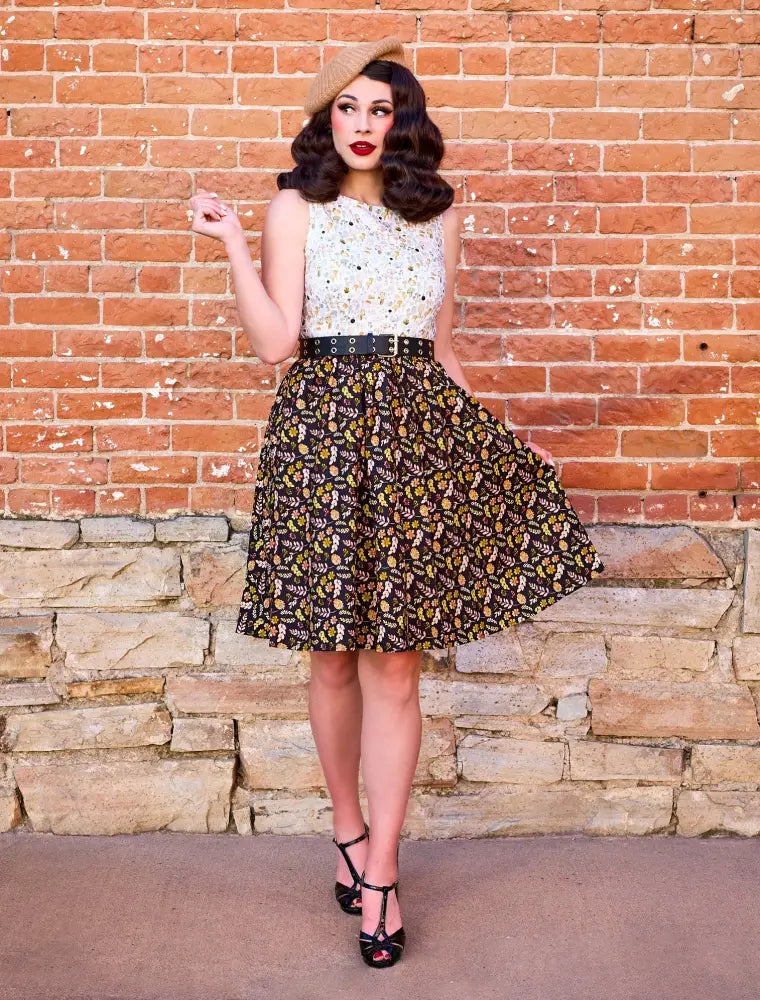 A vintage inspired two piece dress with a white embellished top and dark brown floral skirt with gold accents