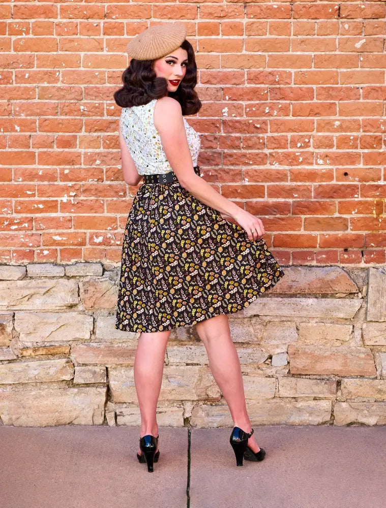 A woman wears the snailing along vintage 1950s floral twofer dress with a white lace top and dark brown floral skirt