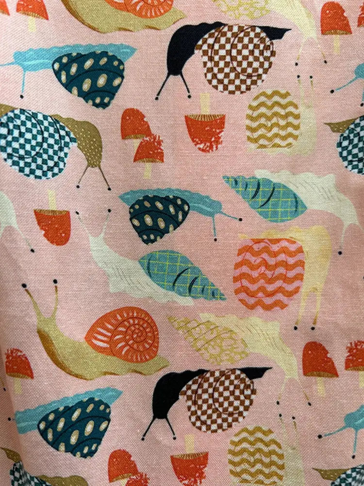 Vintage 1950s style pink cotton dress with pockets featuring playful illustrated snails and colorful textured mushrooms pattern