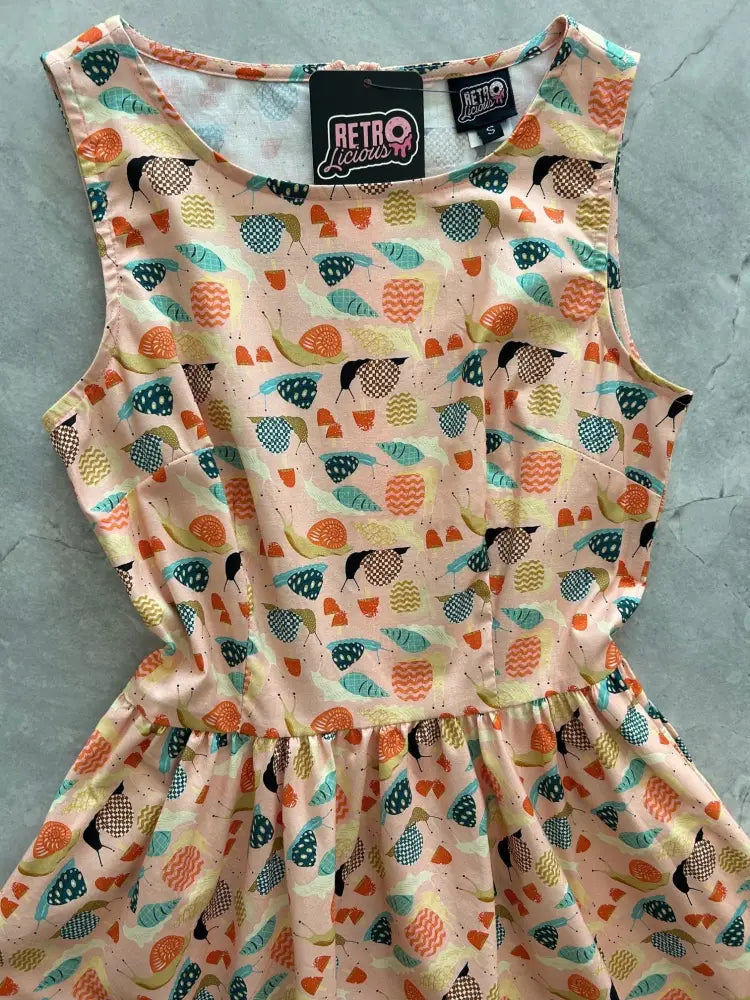 Vintage 1950s style sleeveless peach cotton dress with retro teal orange black yellow bird and geometric patterns and pockets