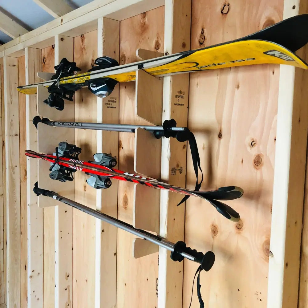 Durable wall mounted snow and water ski storage rack holding yellow and black skis with bindings on wooden wall rack