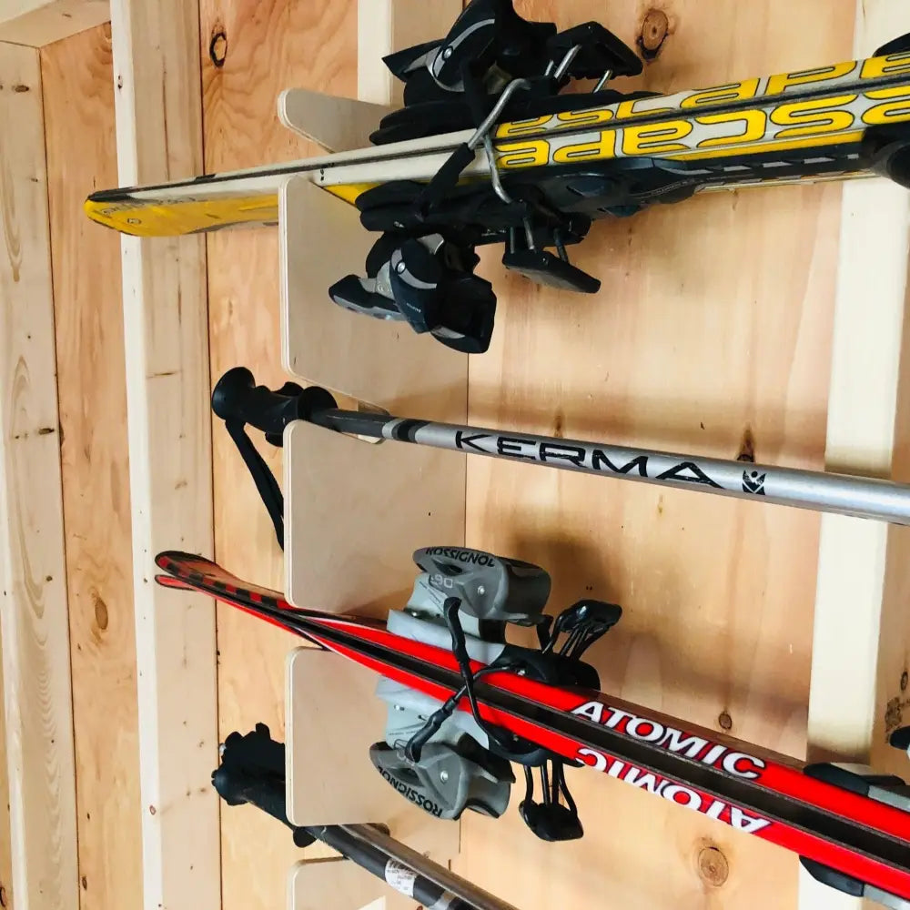 Durable wall mounted snow and water ski storage rack featuring yellow and black skis with bindings on a wooden wall rack