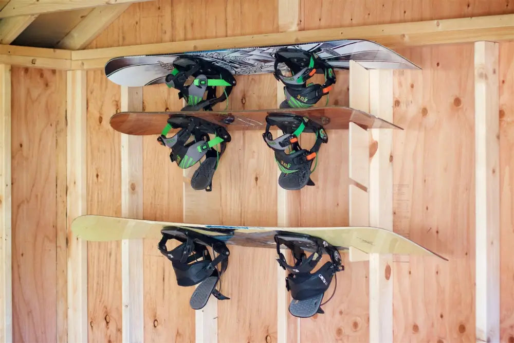 Three snowboards with bindings mounted vertically on a birch plywood stud mounted snowboard and skateboard rack