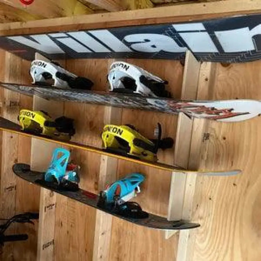 A black and white villain snowboard with sleek modern design mounted on a birch plywood stud mounted rack