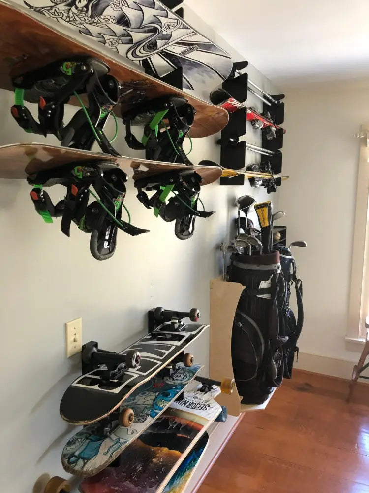 Black and green snowboard bindings displayed on handcrafted minimalist wooden wall mount rack