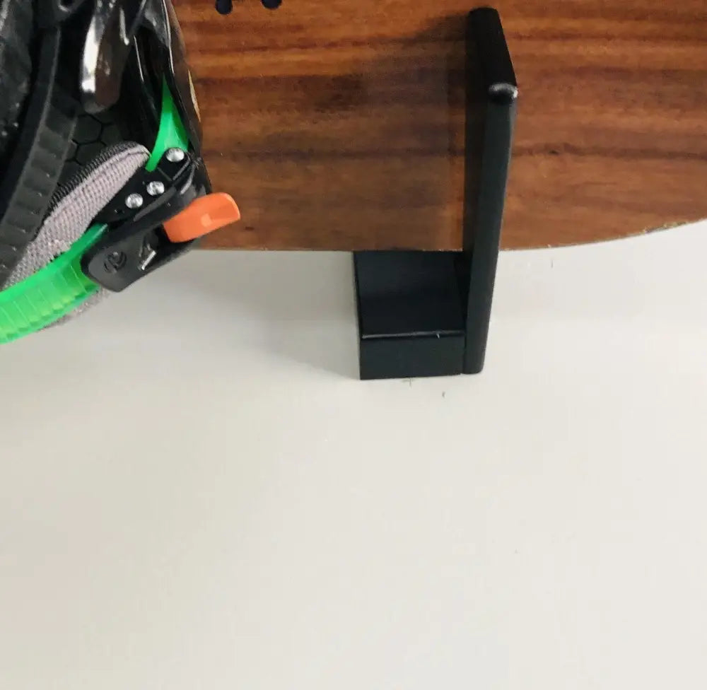 Black plastic bookend holding a snowboard in a handcrafted minimalist snowboard wall mount display rack