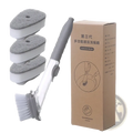 Soap dispensing dish brush with long gray handle white bristles clear plastic body and three gray sponge pads
