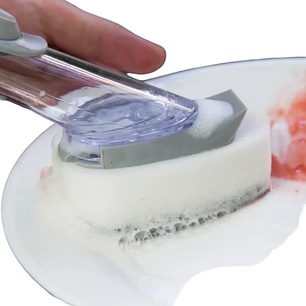 Soap dispensing dish brush with long handle featuring gray transparent plastic scrubber cleaning a white plate