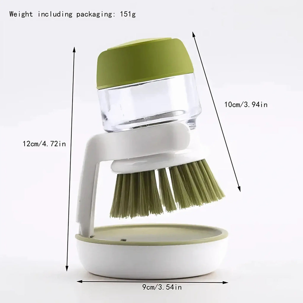 Soap dispensing dish brush with storage base in olive green and white featuring a clear soap reservoir and kitchen bristles