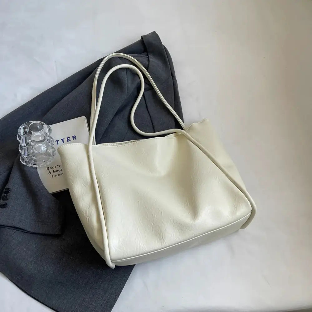 Cream-colored large faux leather minimalist commuter tote bag with matching shoulder strap and sleek design