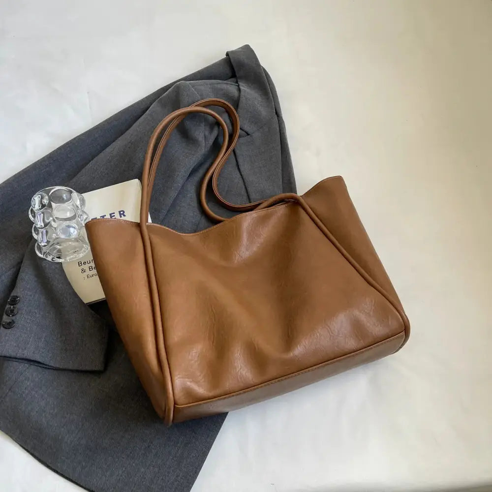 A sleek tan faux leather minimalist large commuter tote bag with long shoulder strap