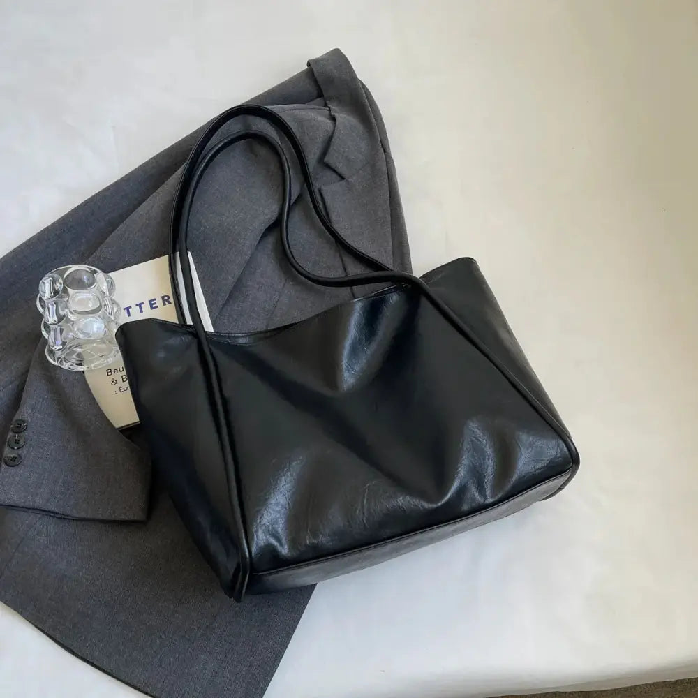Black faux leather large minimalist commuter tote bag with sleek design and long handles for everyday use