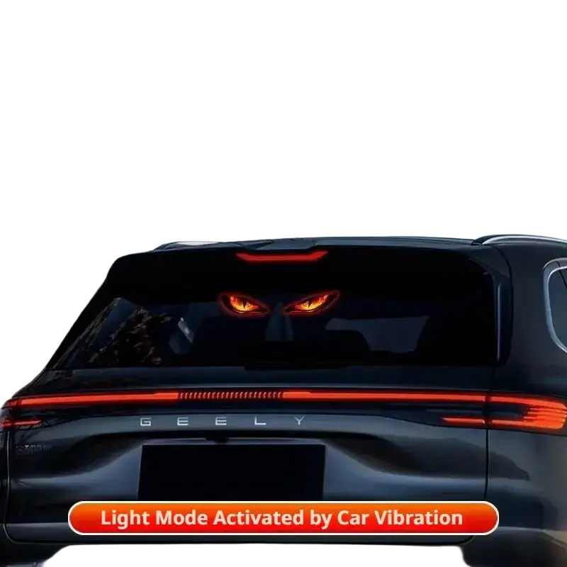 The rear of a black geely suv featuring a solar warning light with suction cups and glowing red devil-eye design taillights