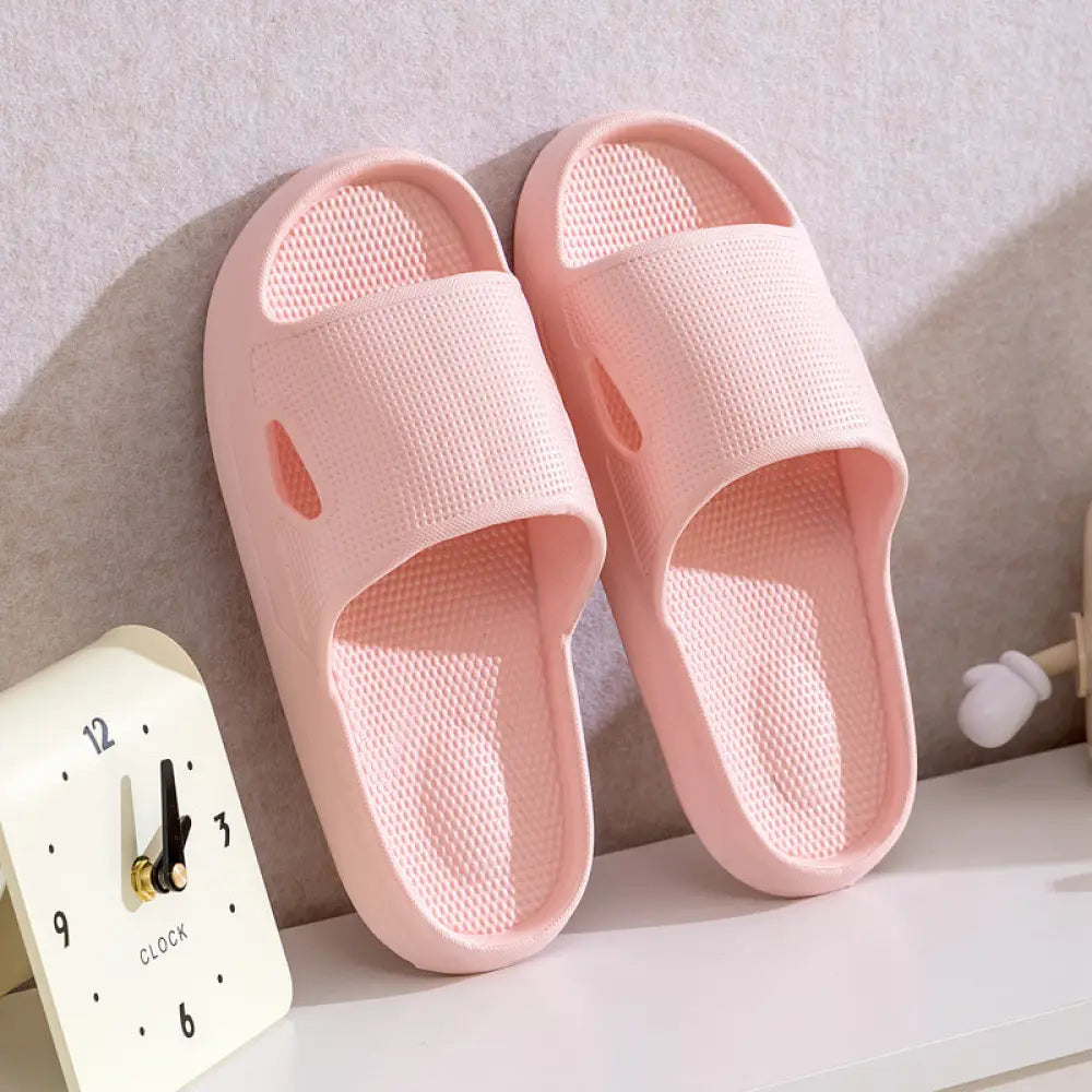 Pair of light pink plastic thick sole non slip cushioned home slides with textured insoles and breathable mesh upper