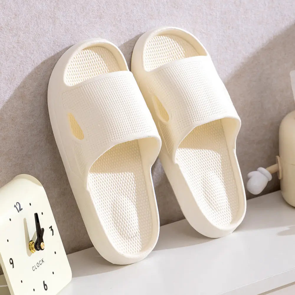 Cream-colored thick sole non slip cushioned home slide sandals with breathable textured plastic mesh and subtle cutouts