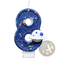 A blue glittery number eight birthday candle with colorful star sprinkles and a white spaceship charm for planetary party