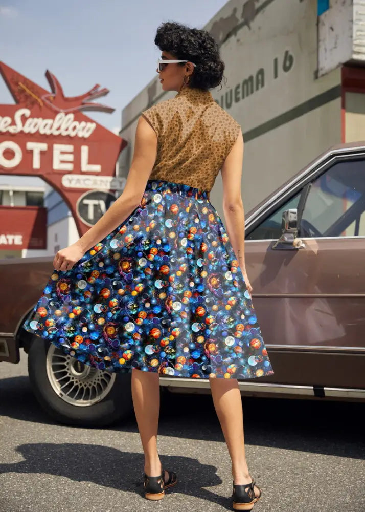 A vibrant blue cotton a-line skirt with fitted waistband featuring a colorful space celestial print and pockets