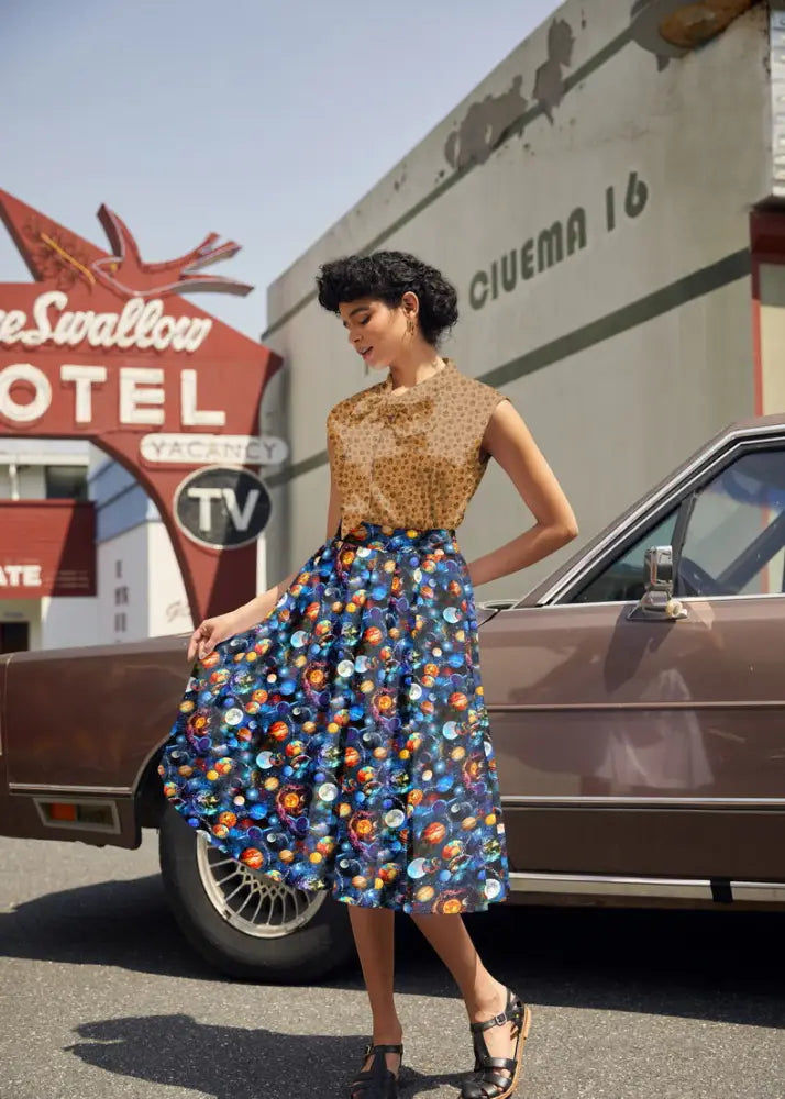A woman wears a sleeveless patterned top with a vibrant blue space celestial print retro cotton Doris skirt with pockets