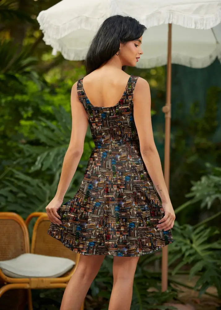 Back view of a sleeveless knee-length spellbinding cityscape print skater dress with backless design and earth tones