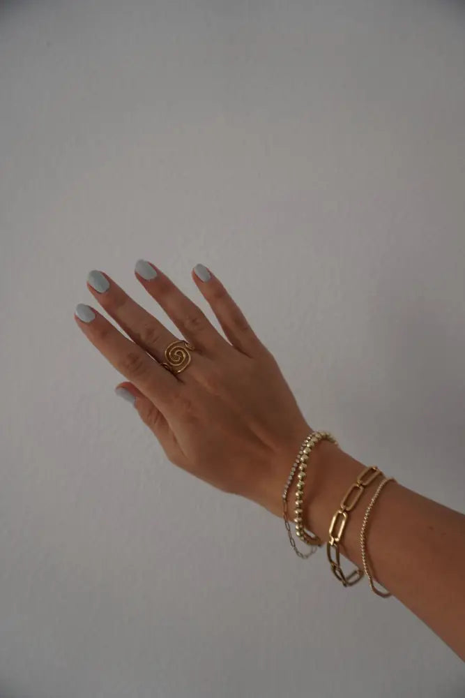 Adjustable gold spiral toe ring with gemstones worn on finger highlighting its elegant design and gold finish
