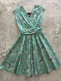 A mint green cotton vintage flare dress with v-neckline and whimsical pink house pattern for Halloween
