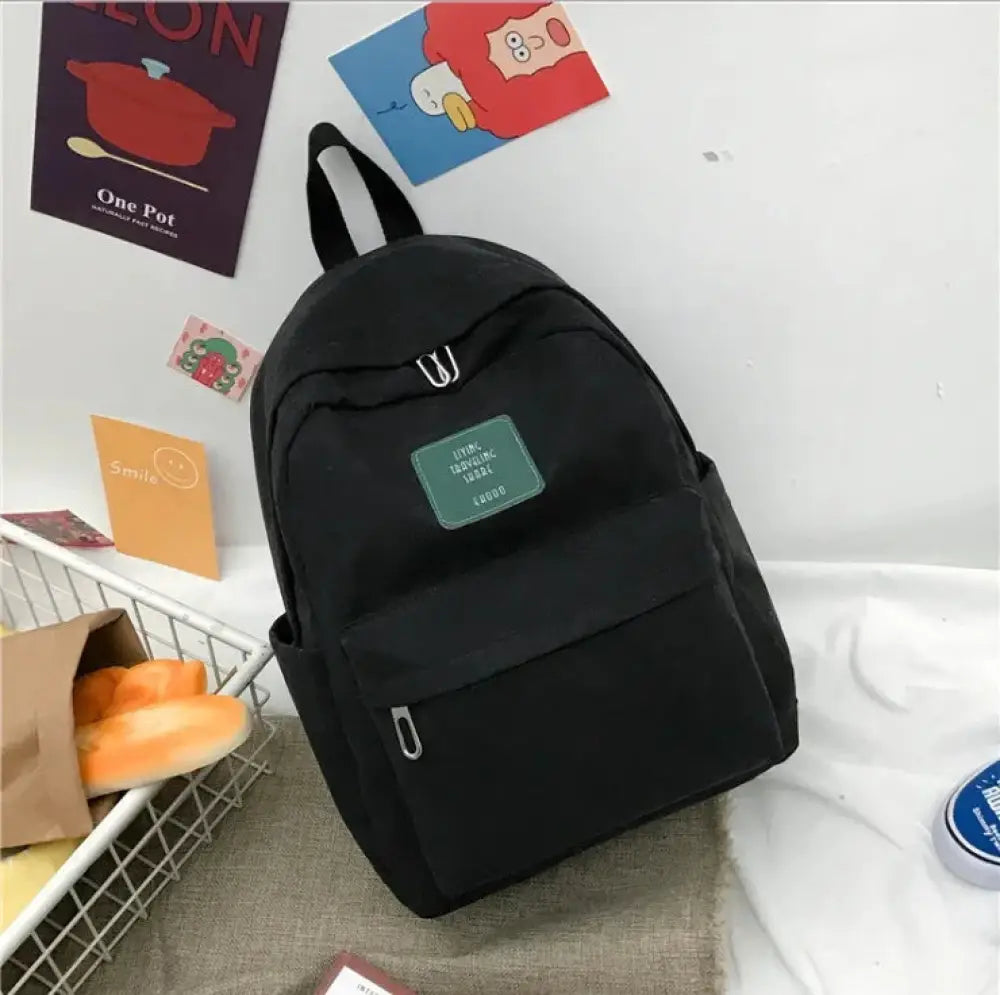 Black canvas women’s Korean corduroy backpack with green patch and silver zipper pulls for school and travel use