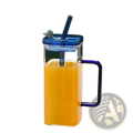 Clear glass pitcher with blue lid handle and straw filled with orange juice square glass cup with lid and straw 12oz
