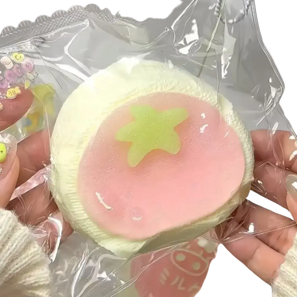 A soft pastel pink and pale yellow squeeze toy slow rising dessert with a green star for stress relief