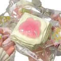 A stack of pastel green square squeeze toys with pink jelly-like centers and glittery details for stress relief