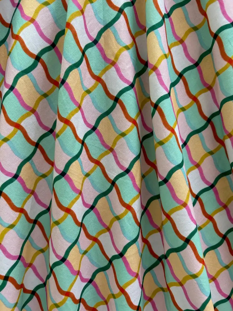 A vibrant squiggly greta vintage cotton v neck dress with pockets features a flowing skirt with multicolor wavy lines
