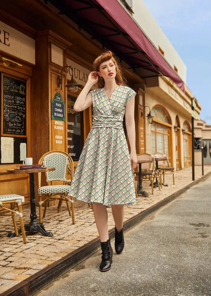 A woman wears a squiggly greta vintage cotton v-neck dress with pockets in light green and white plaid pattern