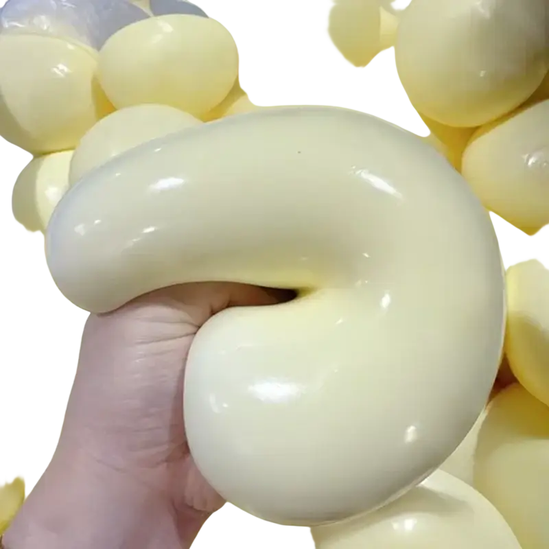 Cream-colored glossy silicone squishy ball with smooth flexible texture and s-shape for stress relief sensory use