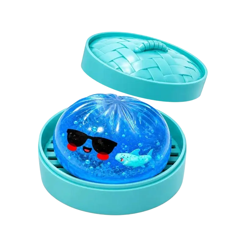 A translucent blue gel-filled squishy dumpling stress ball with a cartoon shark and sunglasses in a turquoise woven container finished goods