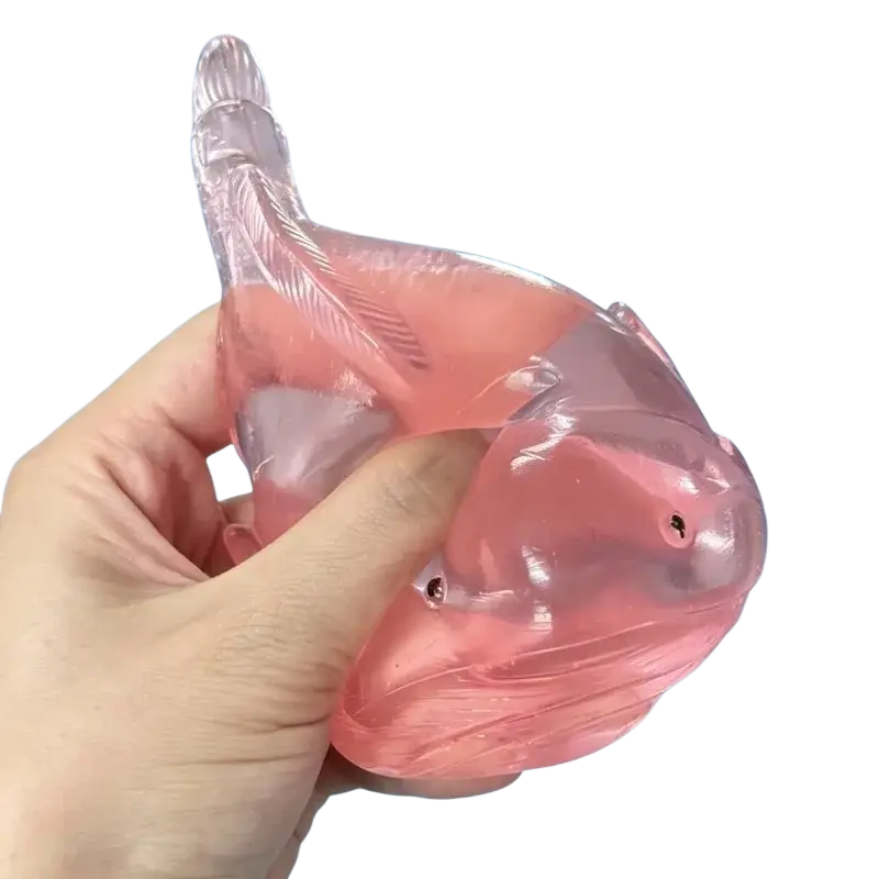 Translucent pink fish-shaped squishy whale fidget toy stress ball with detailed fins and a glossy finish