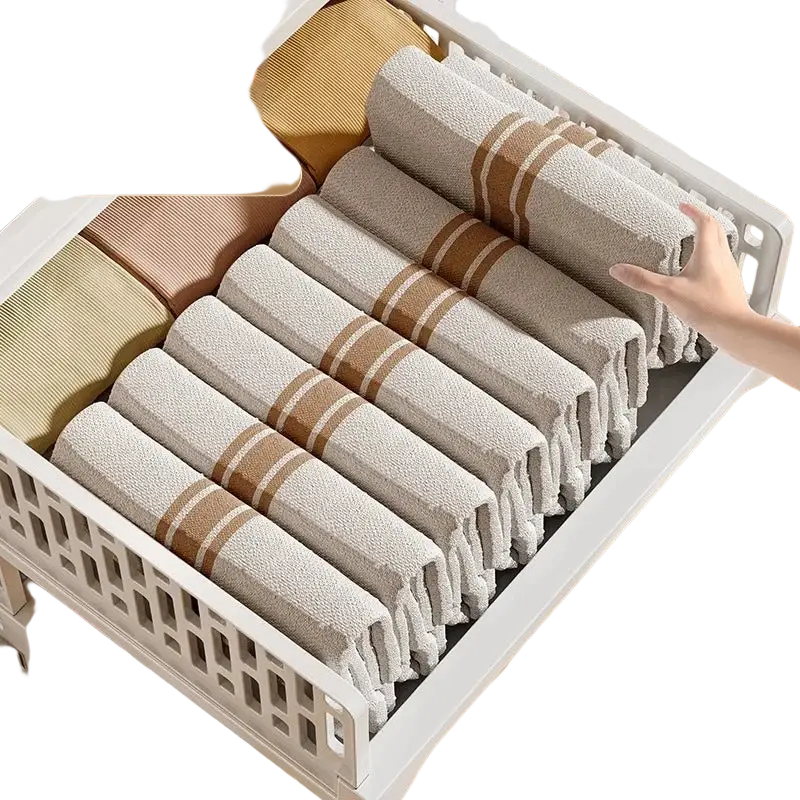 Beige and brown striped towels neatly rolled in a white plastic stackable wardrobe drawer organizer for folding storage