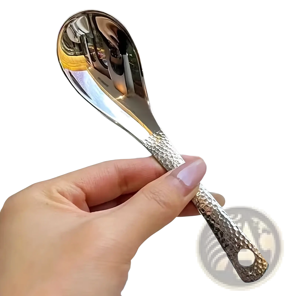 A sleek hammered silver stainless steel dessert spoon with a reflective bowl and textured handle
