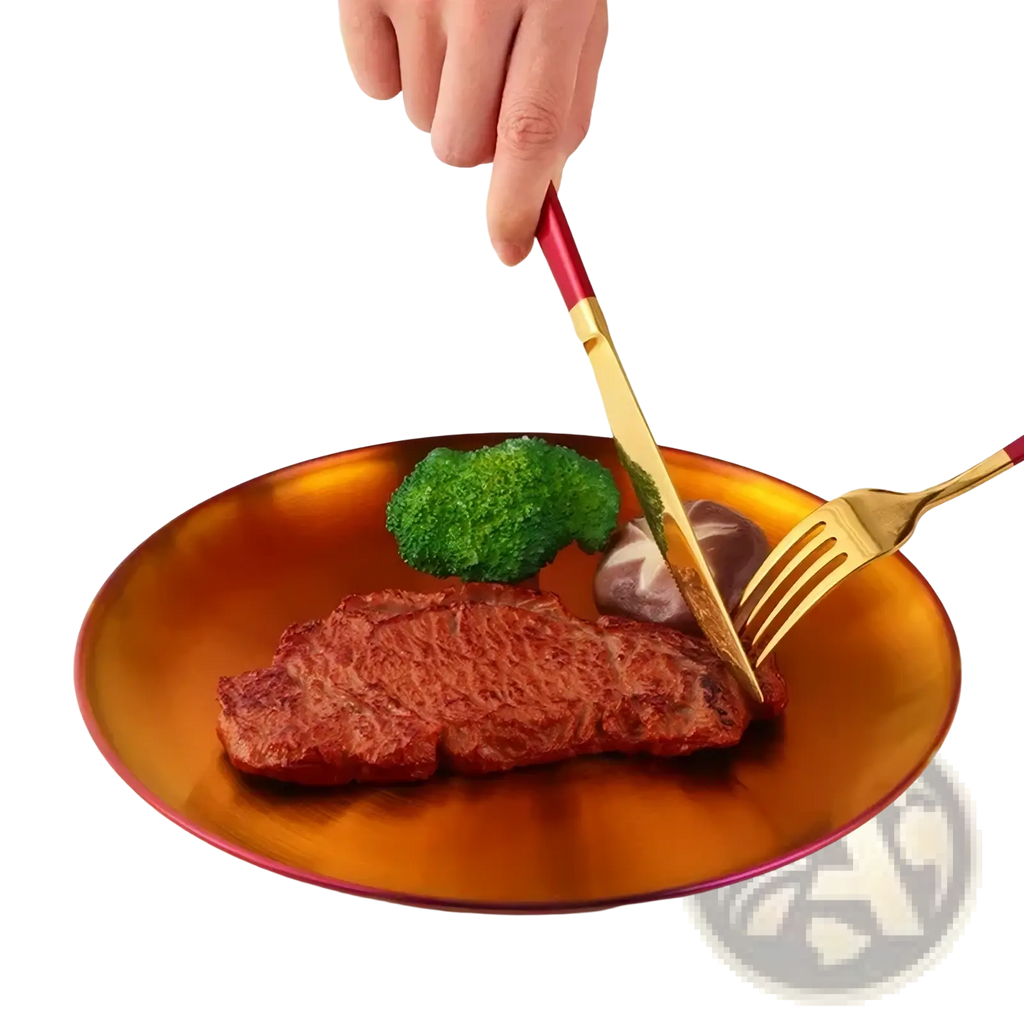 Stainless steel dinner plate with a glossy amber finish and a golden fork and knife set with red handles resting on it
