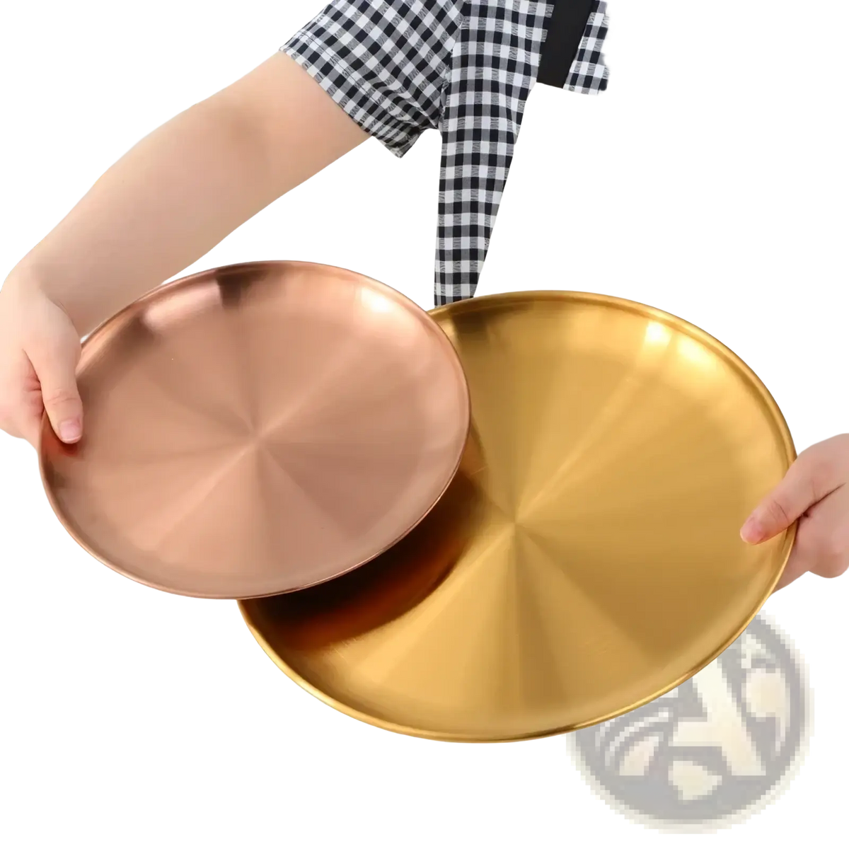 Two round metallic stainless steel dinner plates with brushed copper and gold finish held by hands in apron