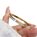 Gold-toned stainless steel bangle bracelet with mother-of-pearl segments and small sparkling diamonds for women